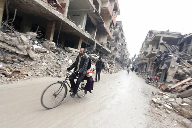 A man rides a bicycle through a damaged street in the Douma neighbourhood of Damascus